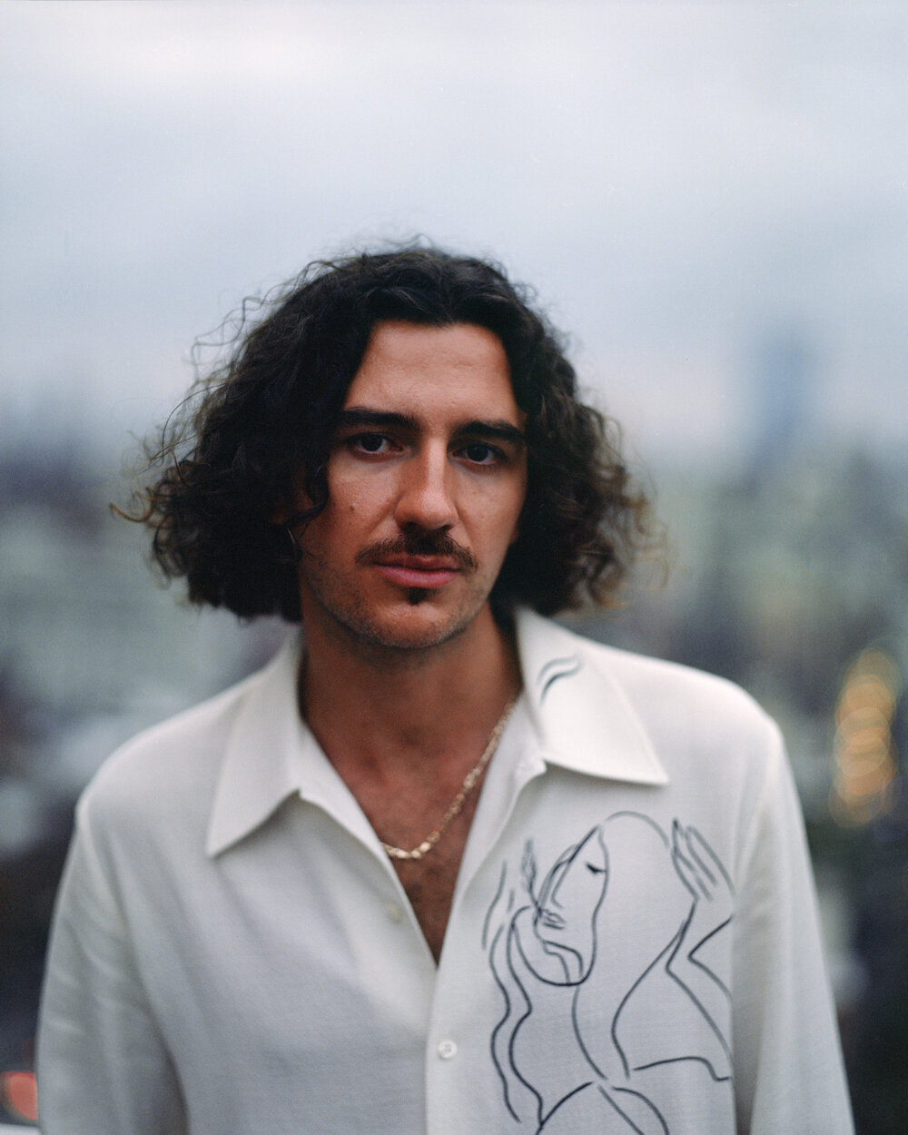 a man with long curly hair wearing a white shirt