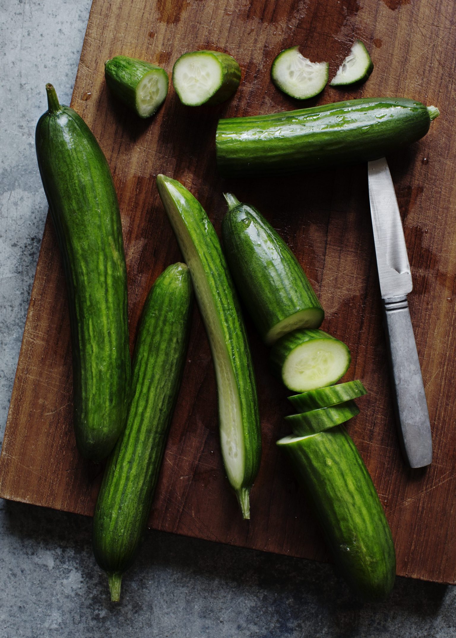 a cucumbers and a knife on a cutting board