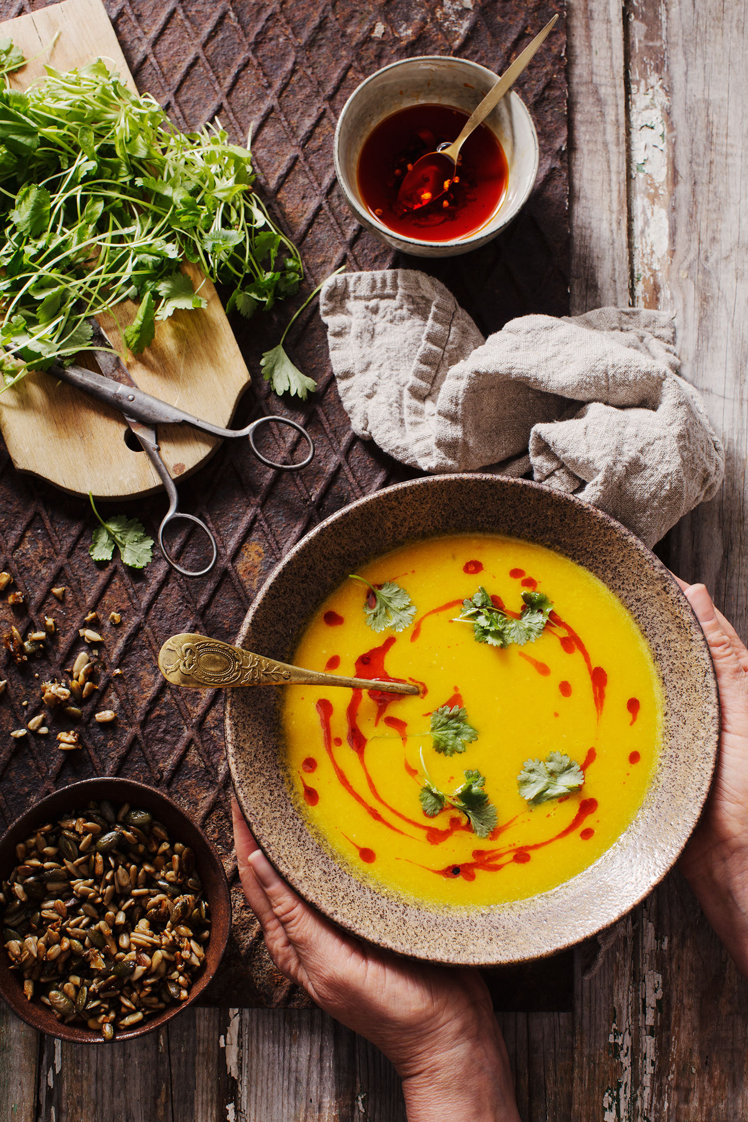 a bowl of soup with a spoon and herbs