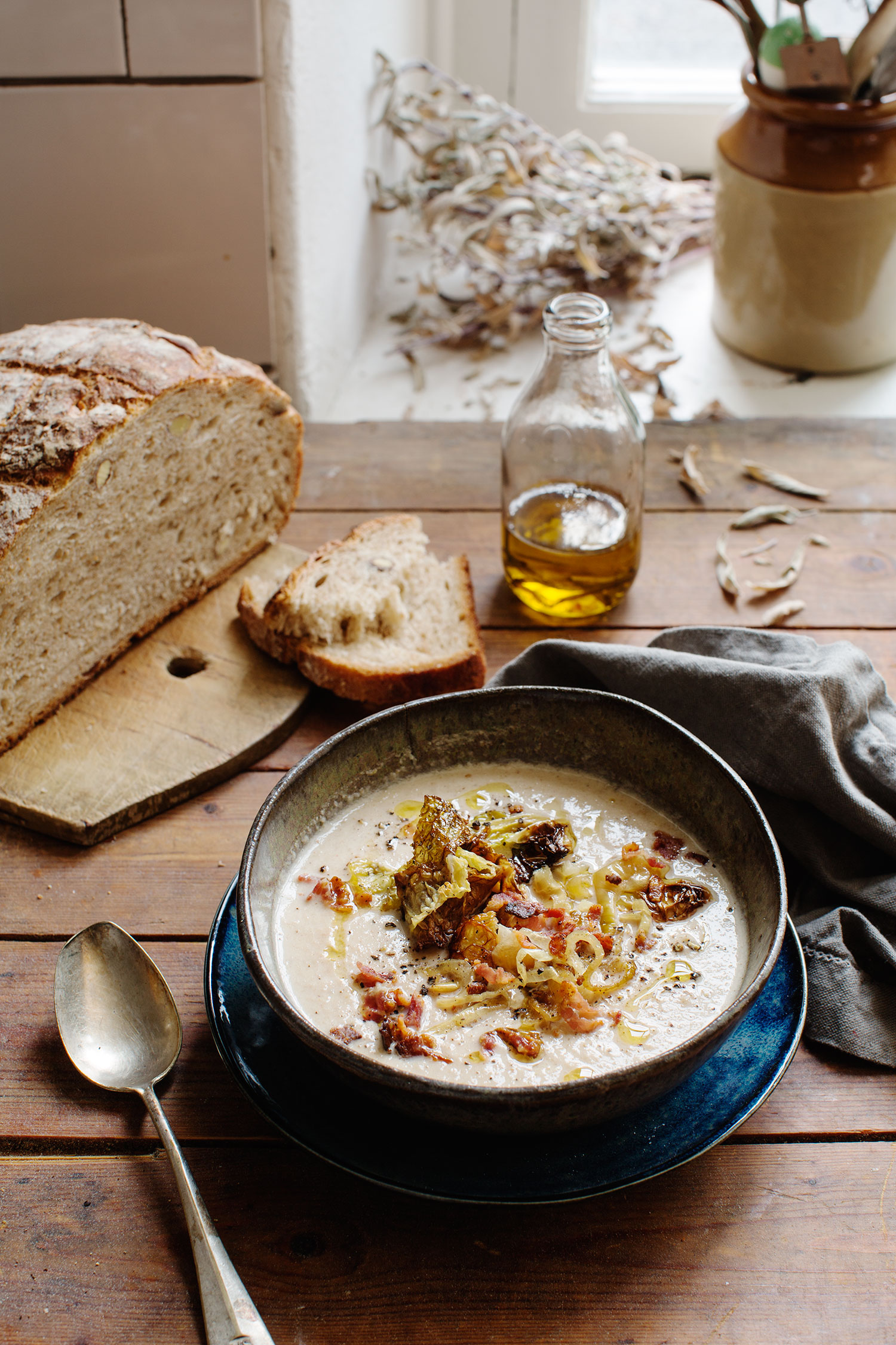 a bowl of soup next to a loaf of bread