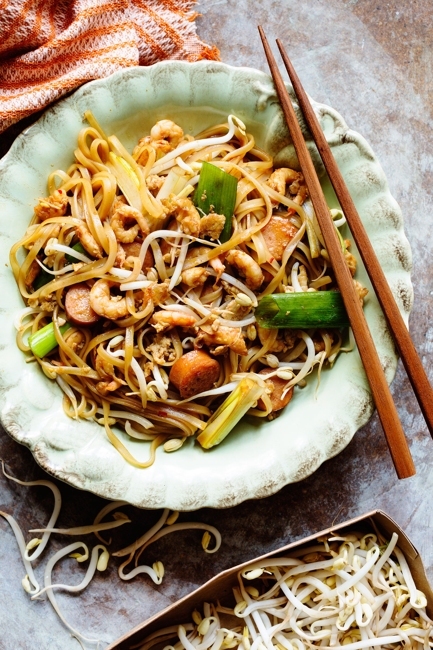 a plate of noodles with shrimp and vegetables