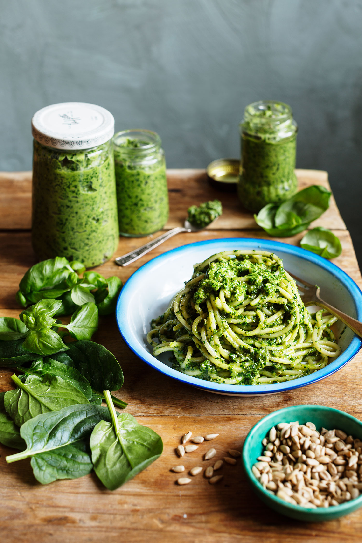 a plate of spaghetti and pesto on a table