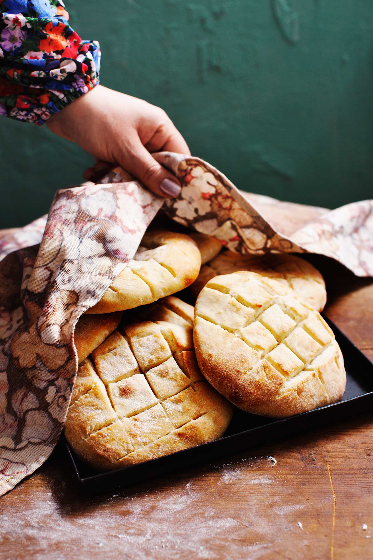 a hand holding a towel over a tray of bread