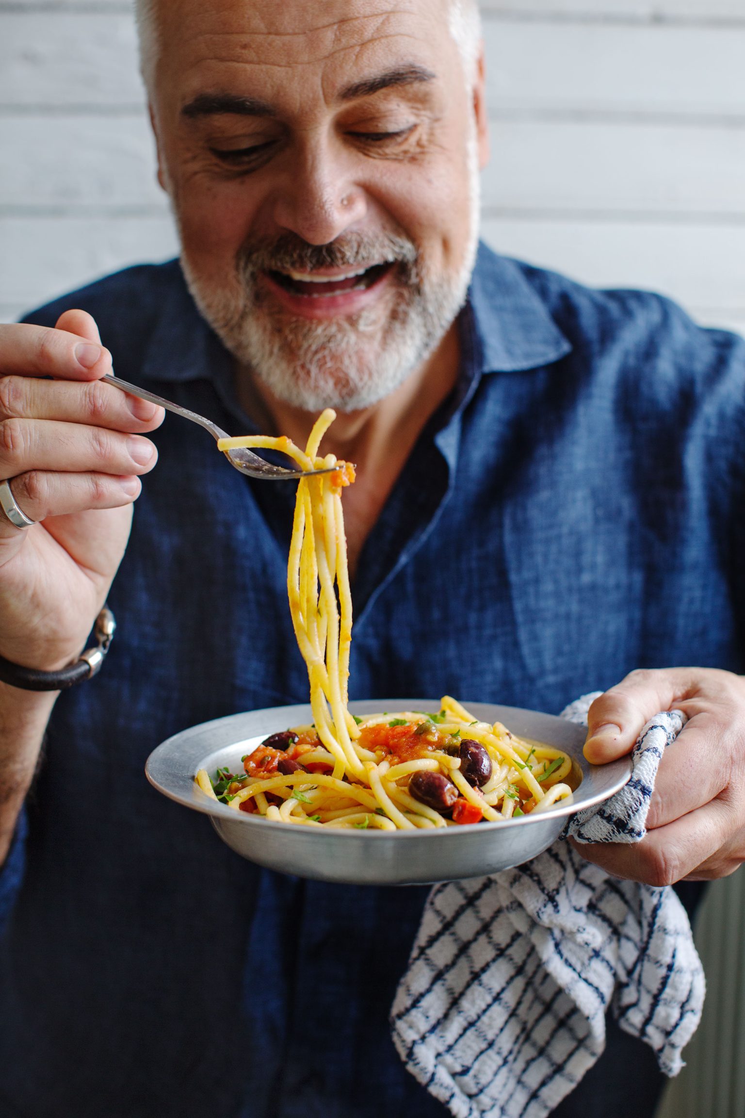a man holding a bowl of spaghetti