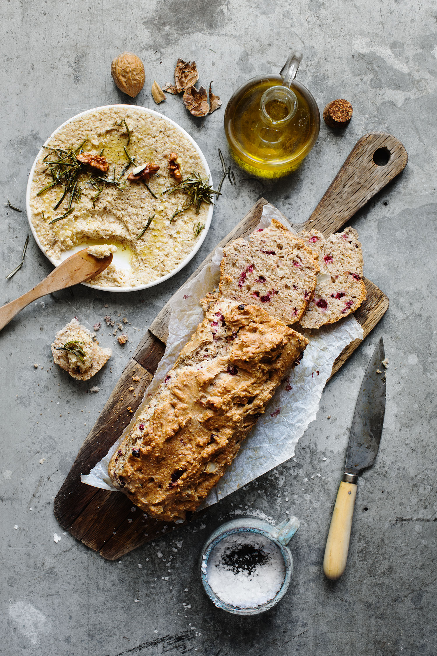 a loaf of bread on a cutting board next to a bowl of food