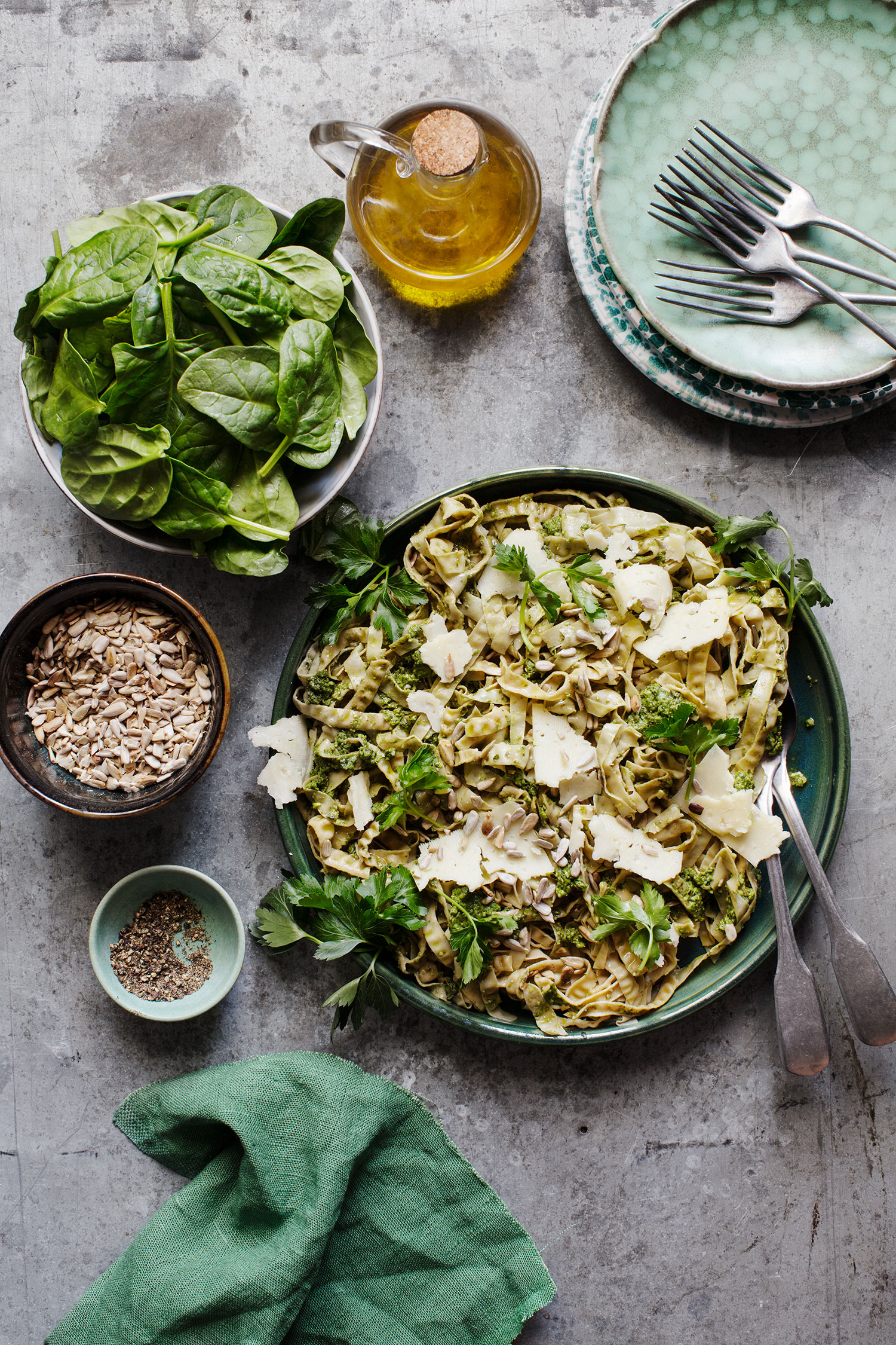 a plate of pasta with greens and a fork and knife