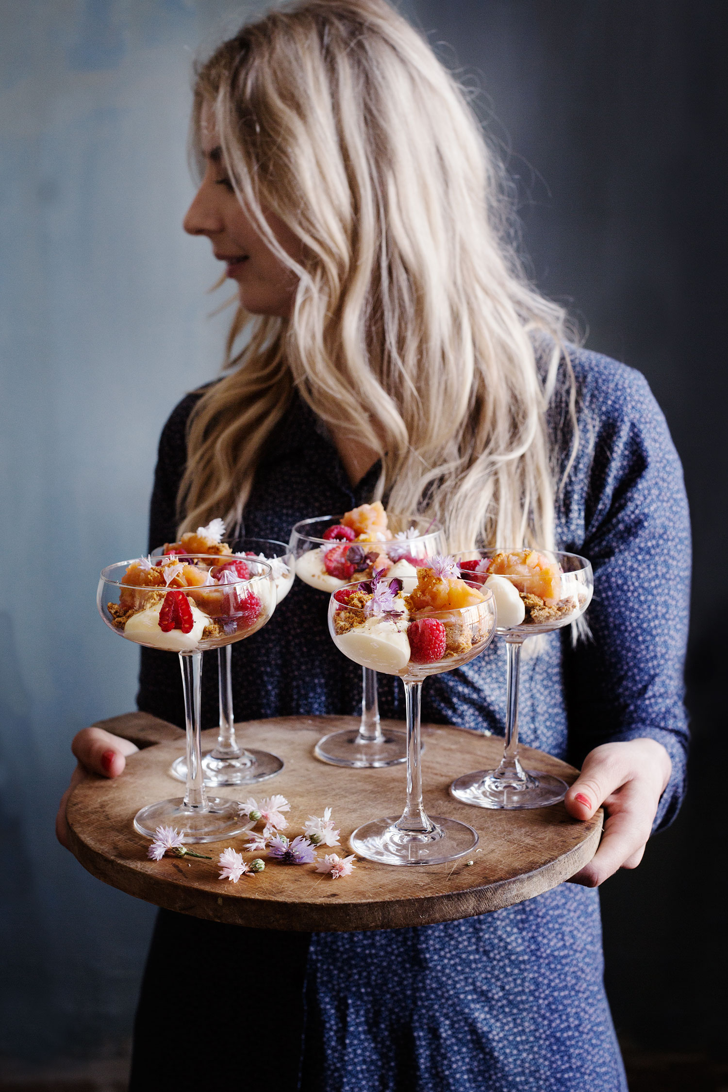 a woman holding a tray of desserts