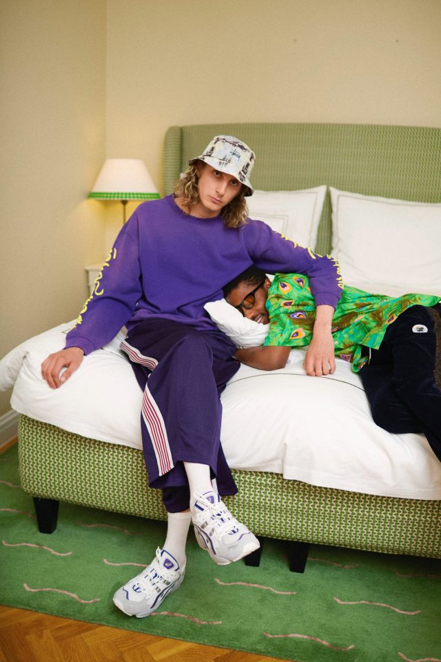 two men sitting on a bed