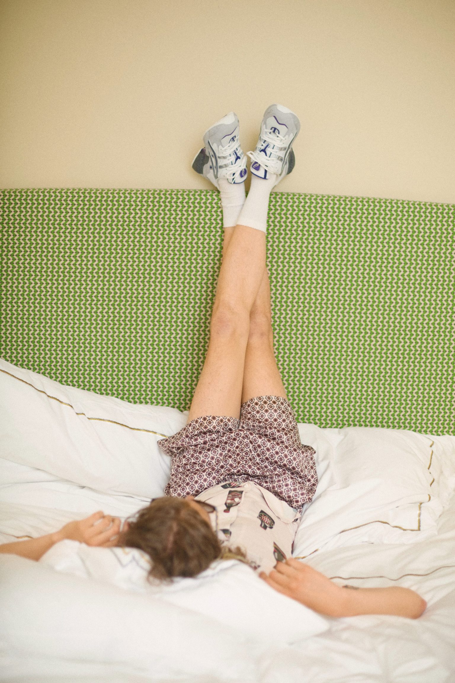 a person lying on a bed with their legs up