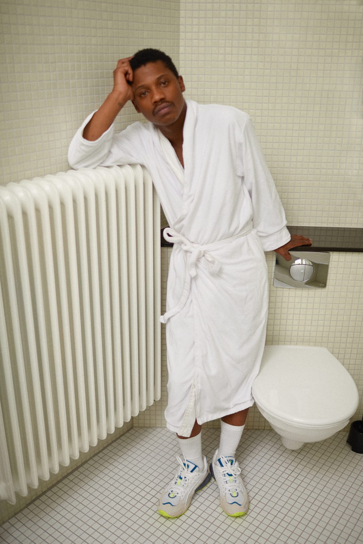 a man in a white robe leaning on a radiator