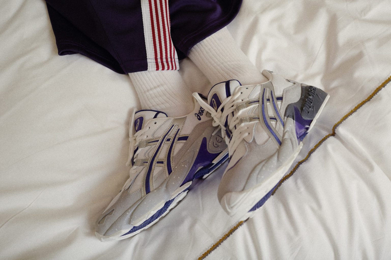 a person's feet wearing white socks and purple and grey sneakers