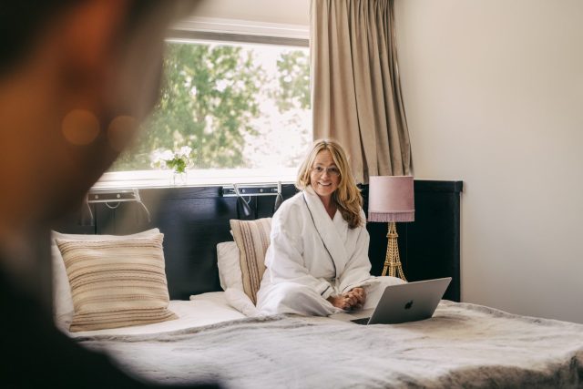 a woman sitting on a bed with a laptop