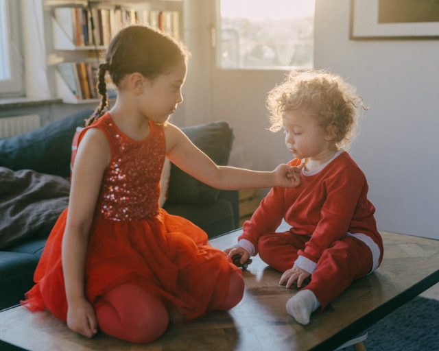 a girl in red dress sitting on a table with another girl in red dress