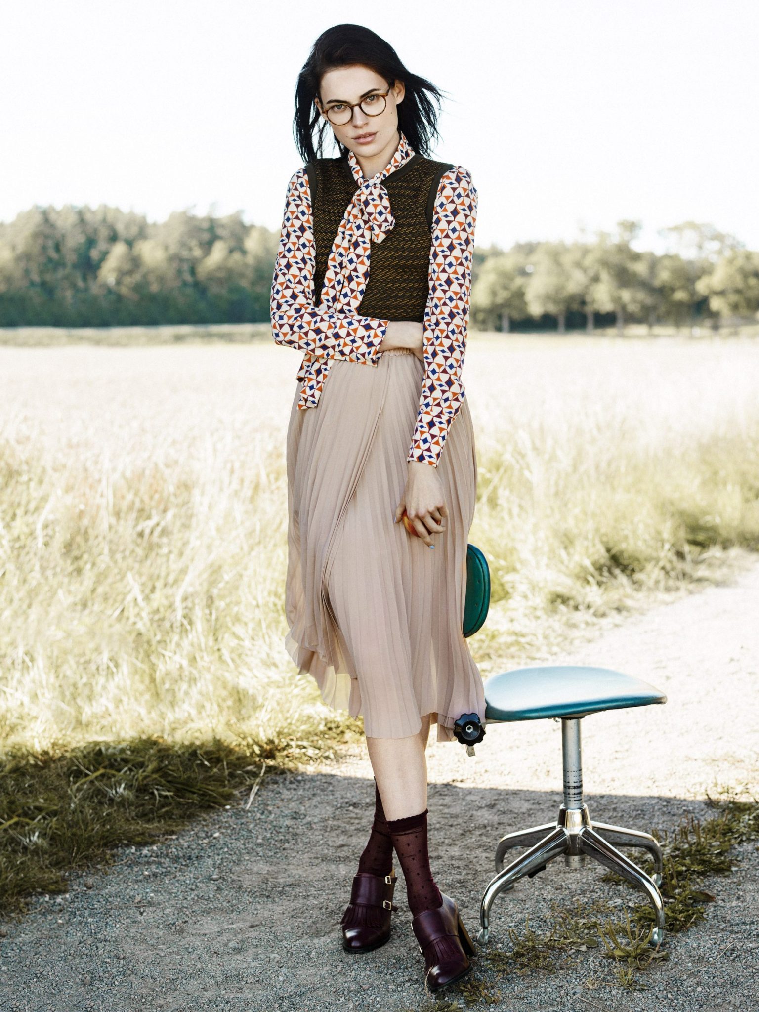 a woman standing on a dirt path with a chair