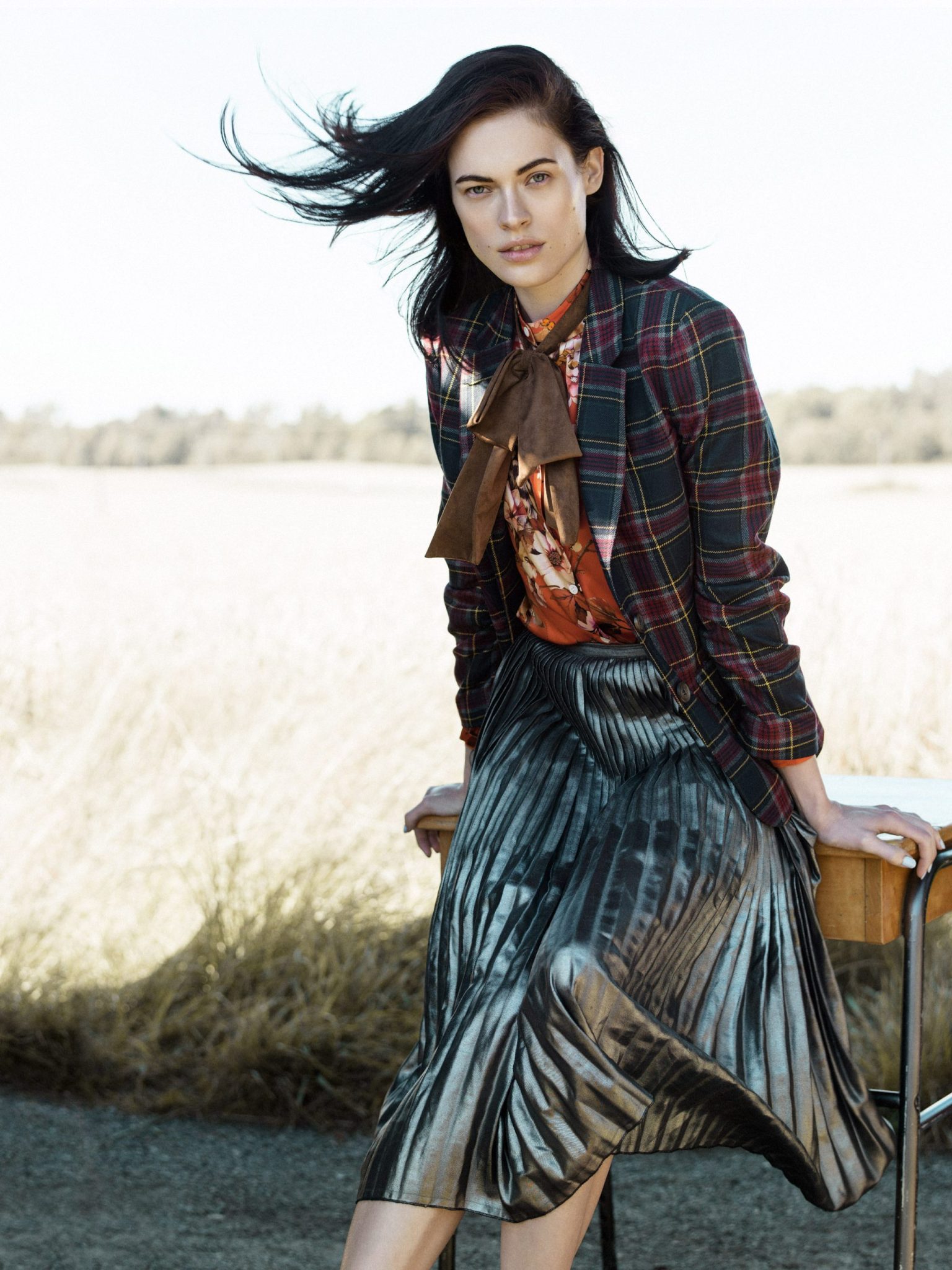a woman with long hair wearing a plaid jacket and pleated skirt