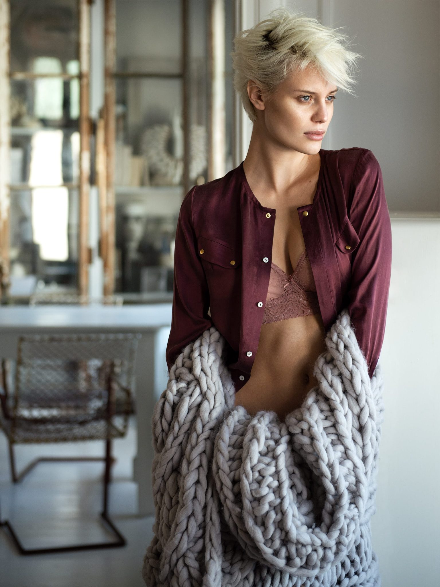 a woman in a red shirt and garment with a large knit blanket