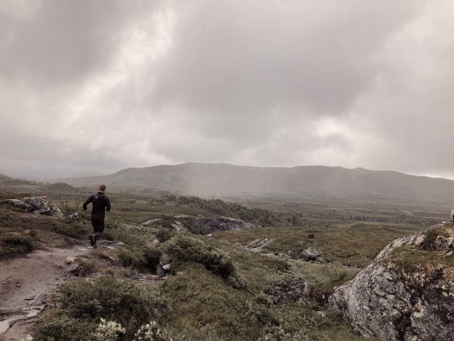 a man running on a trail in a grassy area