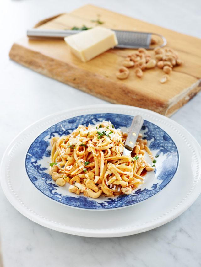 a plate of pasta with a fork and cashews on it