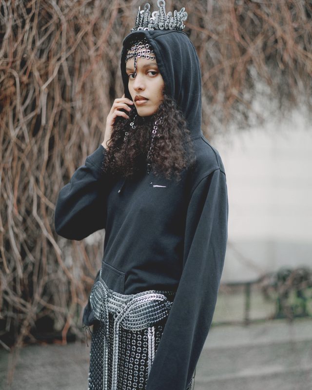 a woman wearing a black hoodie and silver chain around her head