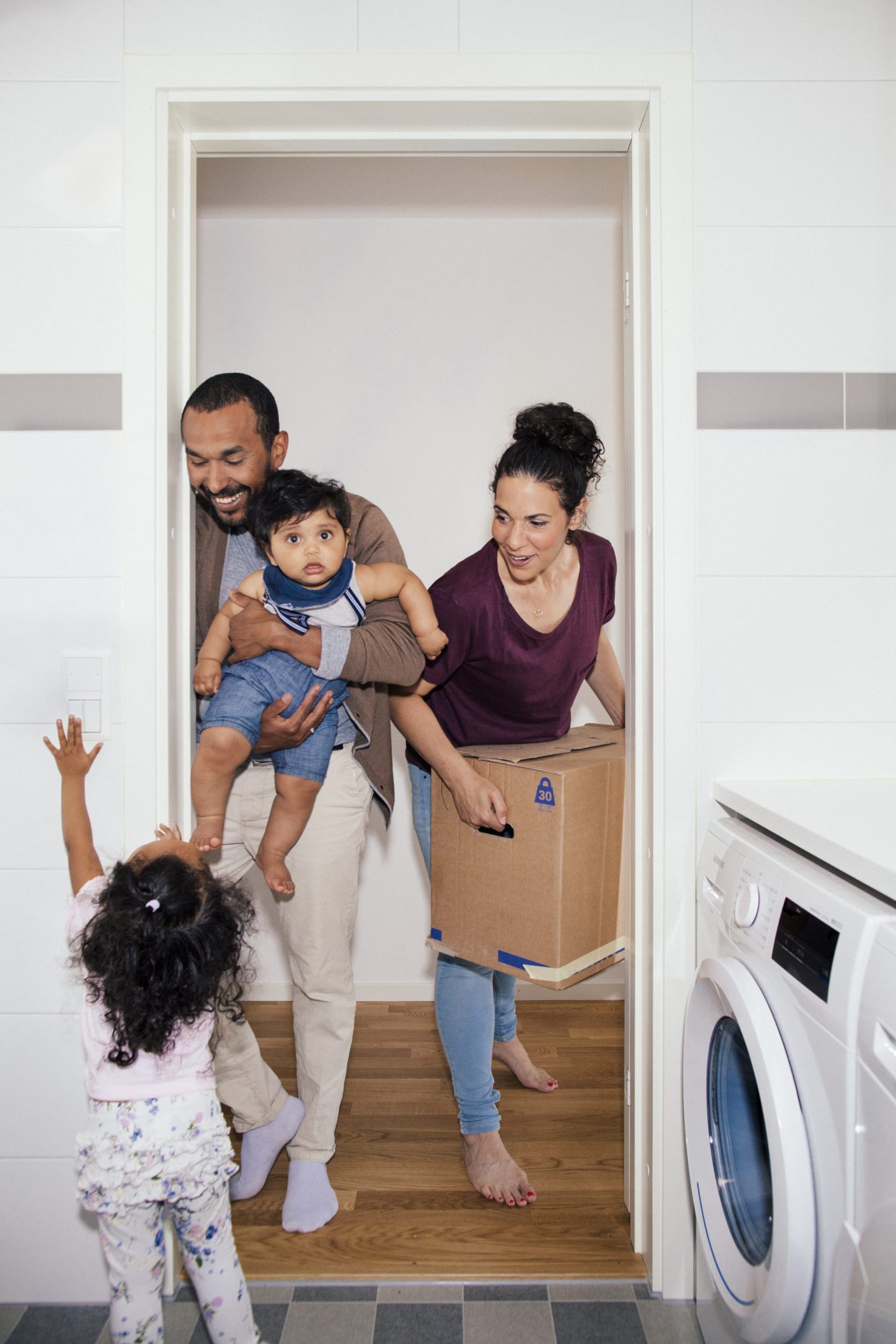 a man woman and child in a room with a box and a washing machine