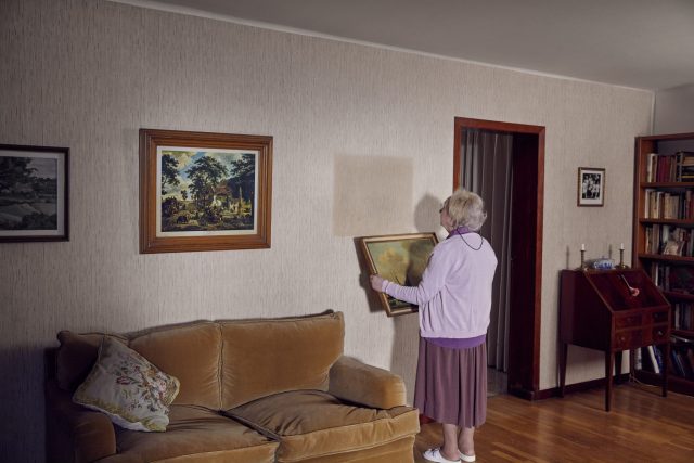a woman standing in a room with a couch and painting on the wall