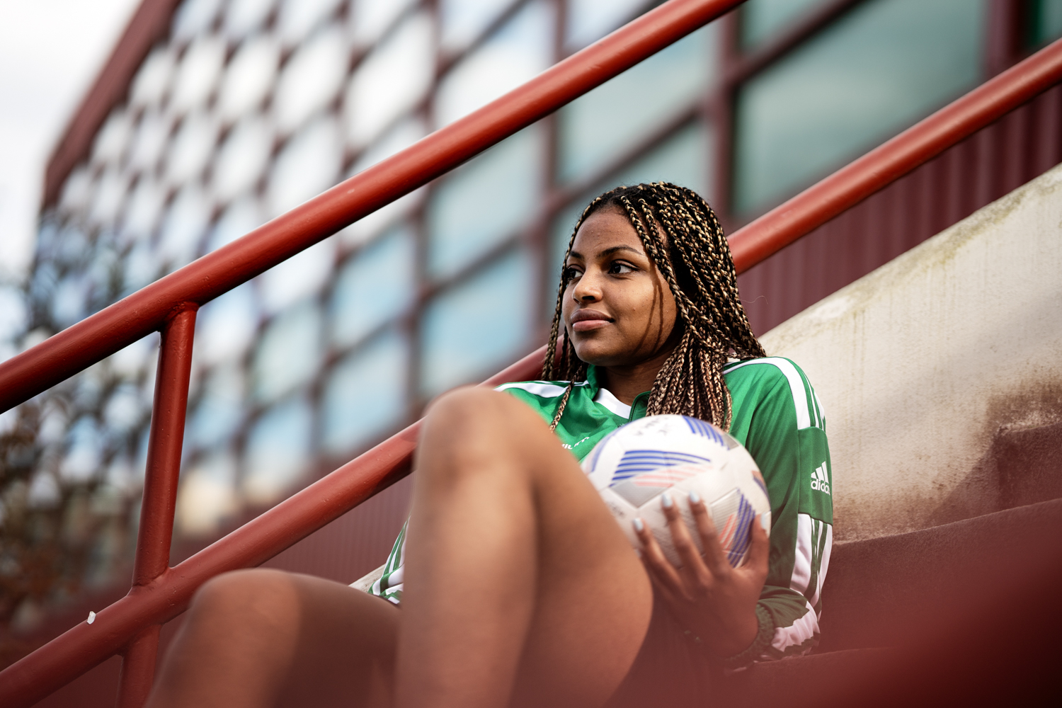 a woman sitting on stairs holding a football ball