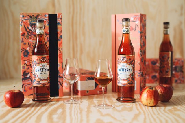 a bottle of liquor next to glasses and fruit