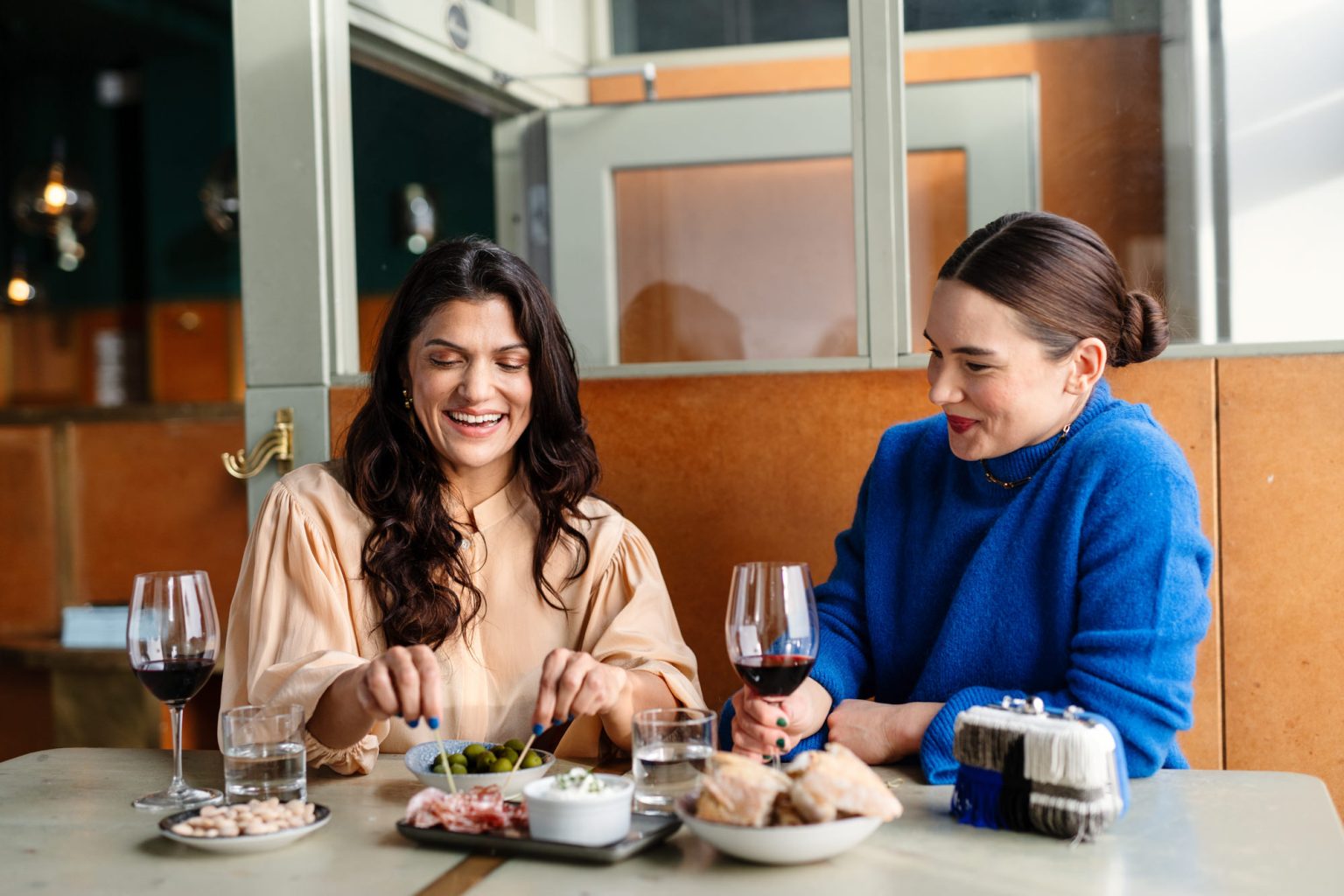 a couple of women sitting at a table with food and drinks