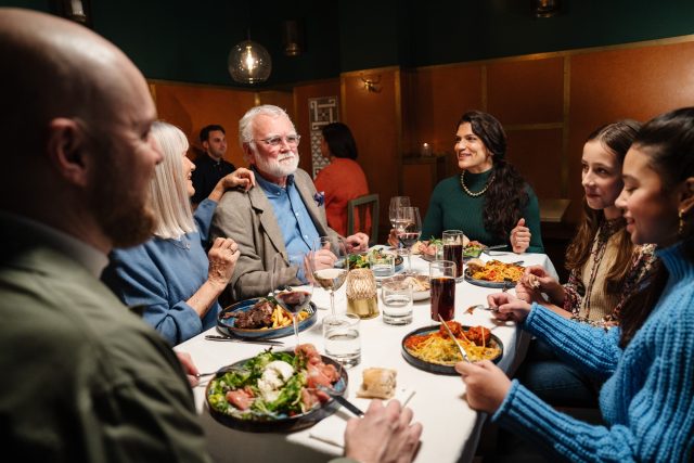 a group of people sitting around a table with food