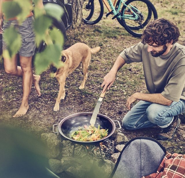 a man cooking food on a grill with a dog