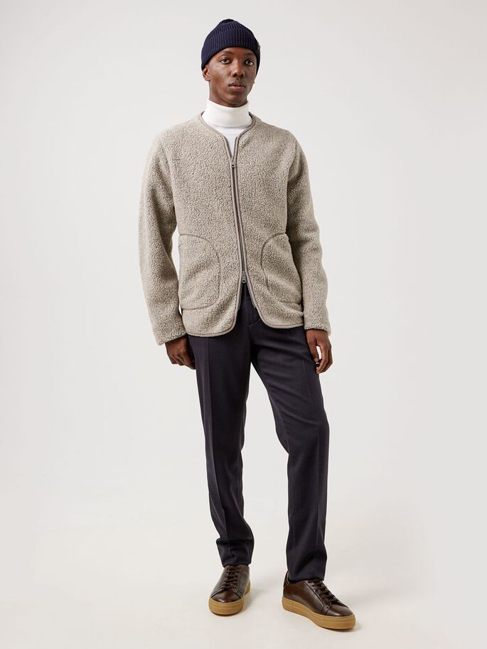 a man in a white turtleneck and black pants