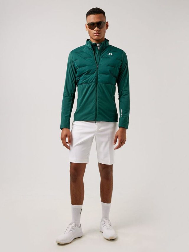 a man wearing a green jacket and white shorts