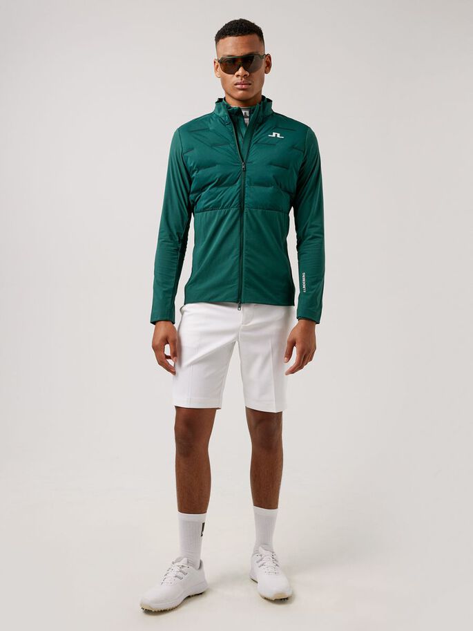 a man wearing a green jacket and white shorts