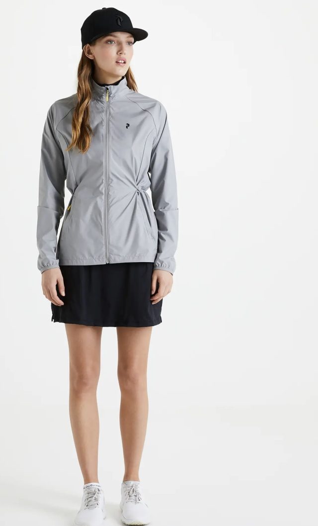 a woman wearing a grey jacket and black skirt