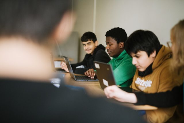 a group of people sitting at a table with laptops