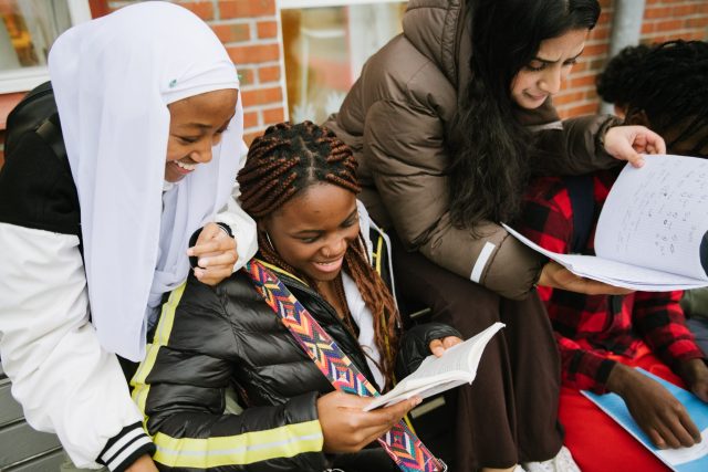a group of women sitting on a bench reading books