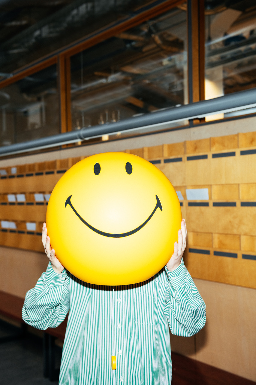 a person holding a yellow balloon with a smiley face