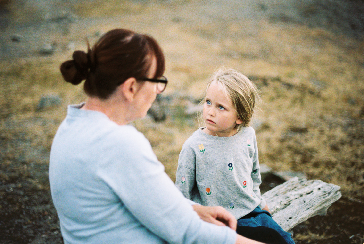 a woman and a child sitting on a log