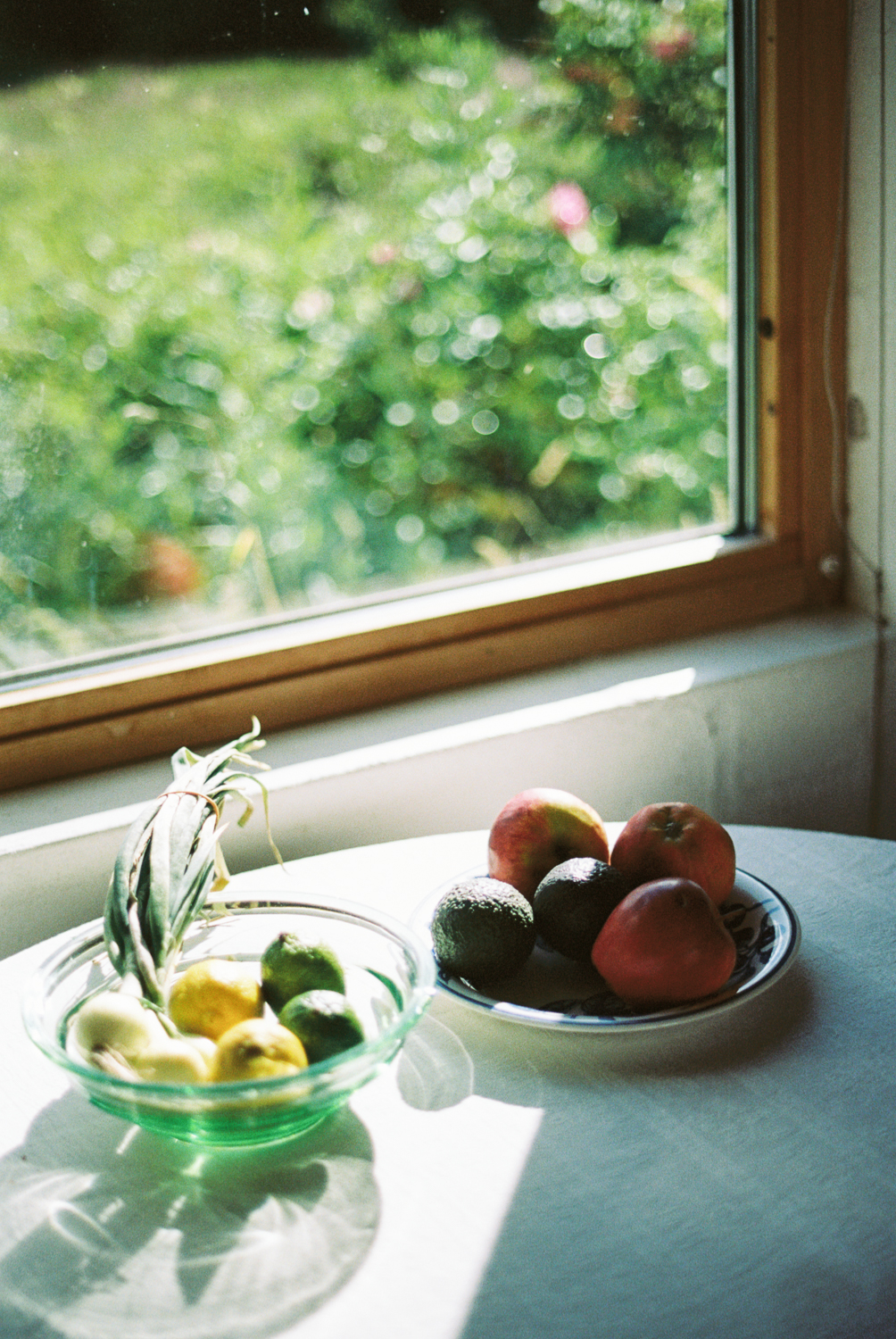 a bowl of fruit on a table next to a window