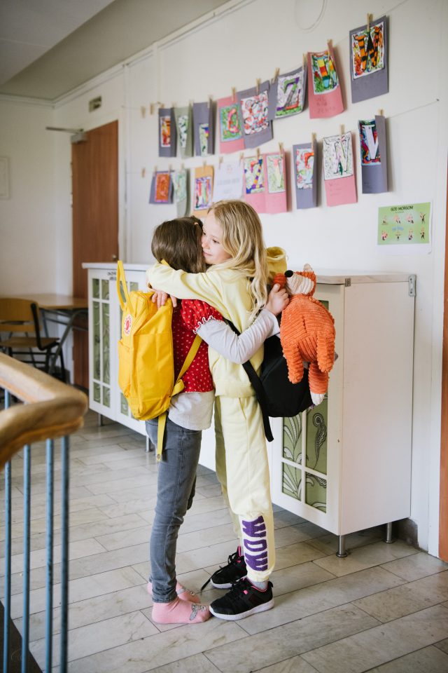 two girls hugging in a hallway