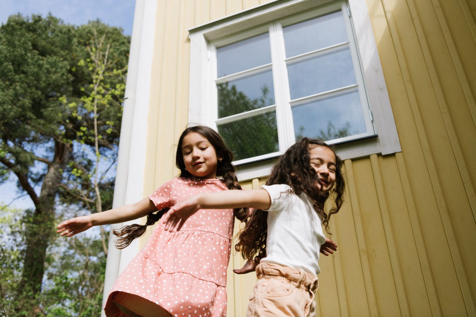 a couple of girls dancing outside a house