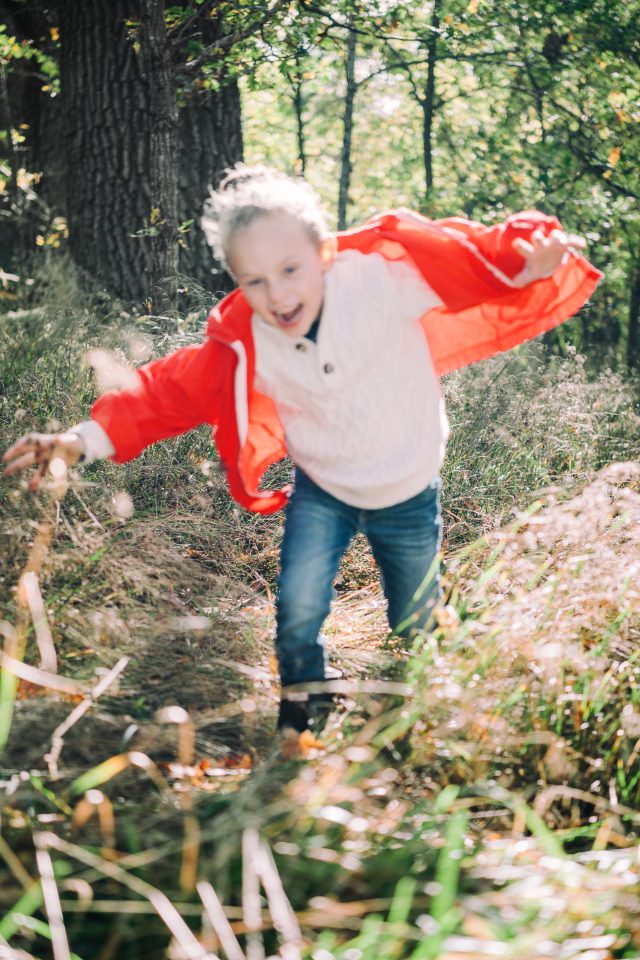 a child in a red jacket running through tall grass