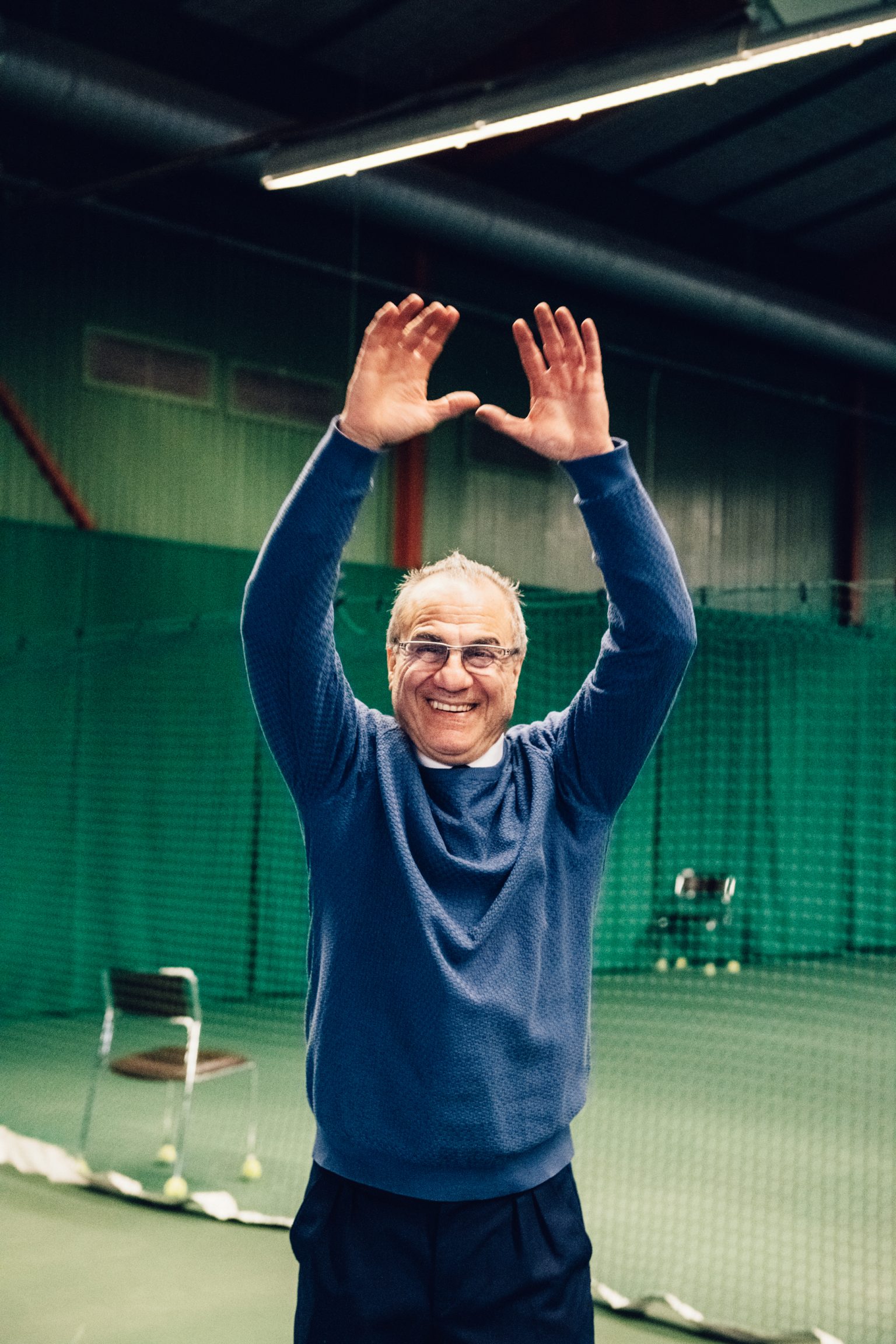 a man in a blue sweater with his hands up