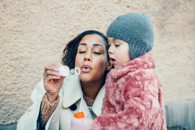 a woman and a child blowing bubbles