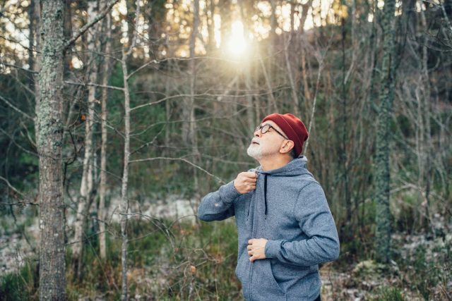 a man in a hat and jacket in a forest
