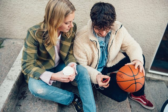 a man and woman sitting on steps with a basketball and a phone