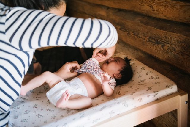 a woman putting on a diaper to a baby