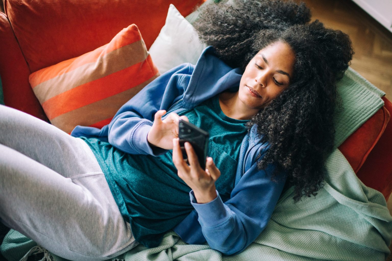 a woman lying on a couch looking at a phone