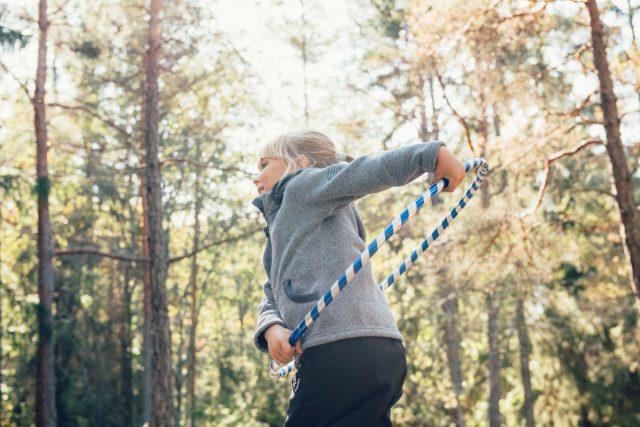 a girl holding a hula hoop in the woods