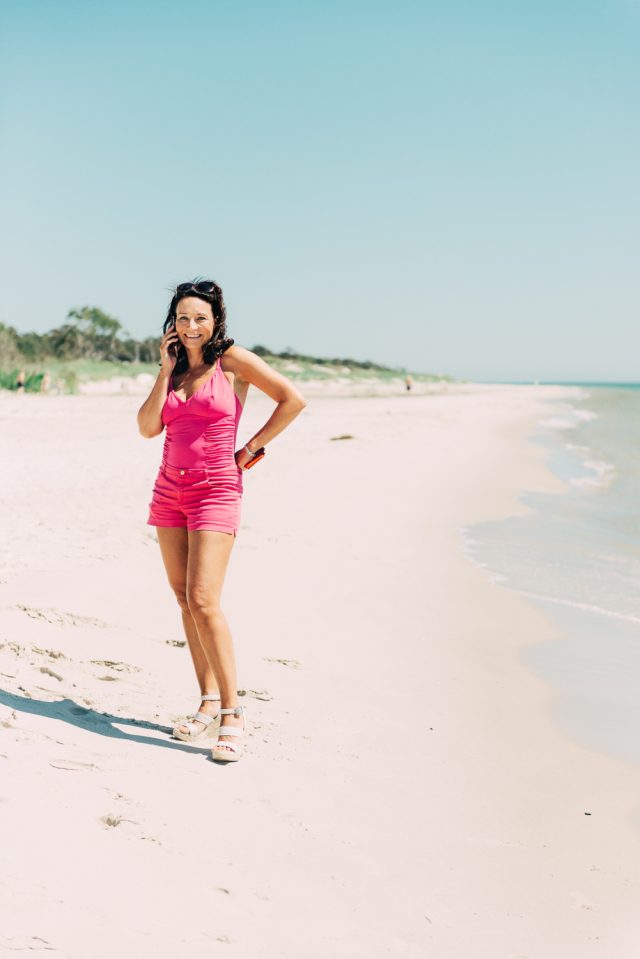 a woman on a beach talking on a cell phone